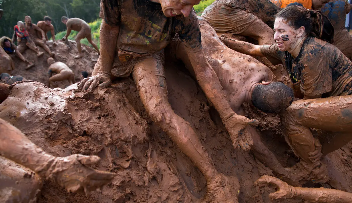 Peserta membantu rekannya untuk melewati kolam lumpur saat mengikuti Mud Day di Tel Aviv, Israel (24/3). Mud day atau Hari Lumpur ini pertama kali diperkenalkan di Paris pada 2013. (AP Photo/Oded Balilty)