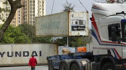 Pekerja menyaksikan kontainer berpendingin untuk jenazah diturunkan di sebuah lahan kosong dekat rumah duka di Hong Kong,  Senin (7/3/2022). Rumah sakit Kong sudah mulai menggunakan wadah berpendingin untuk menyimpan jenazah sebelum dimakamkan. (AP Photo/Vincent Yu)