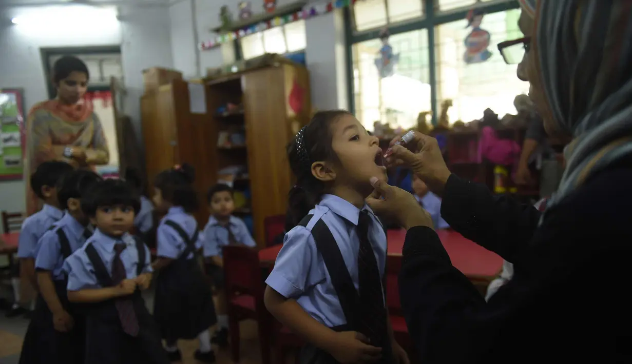 Pekerja kesehatan Pakistan memberi vaksin polio ke seorang anak di Karachi (9/4). Pakistan adalah salah satu dari hanya dua negara di dunia di mana polio, penyakit masa kecil yang melumpuhkan. (AFP Photo/Rizwan Tabassum)
