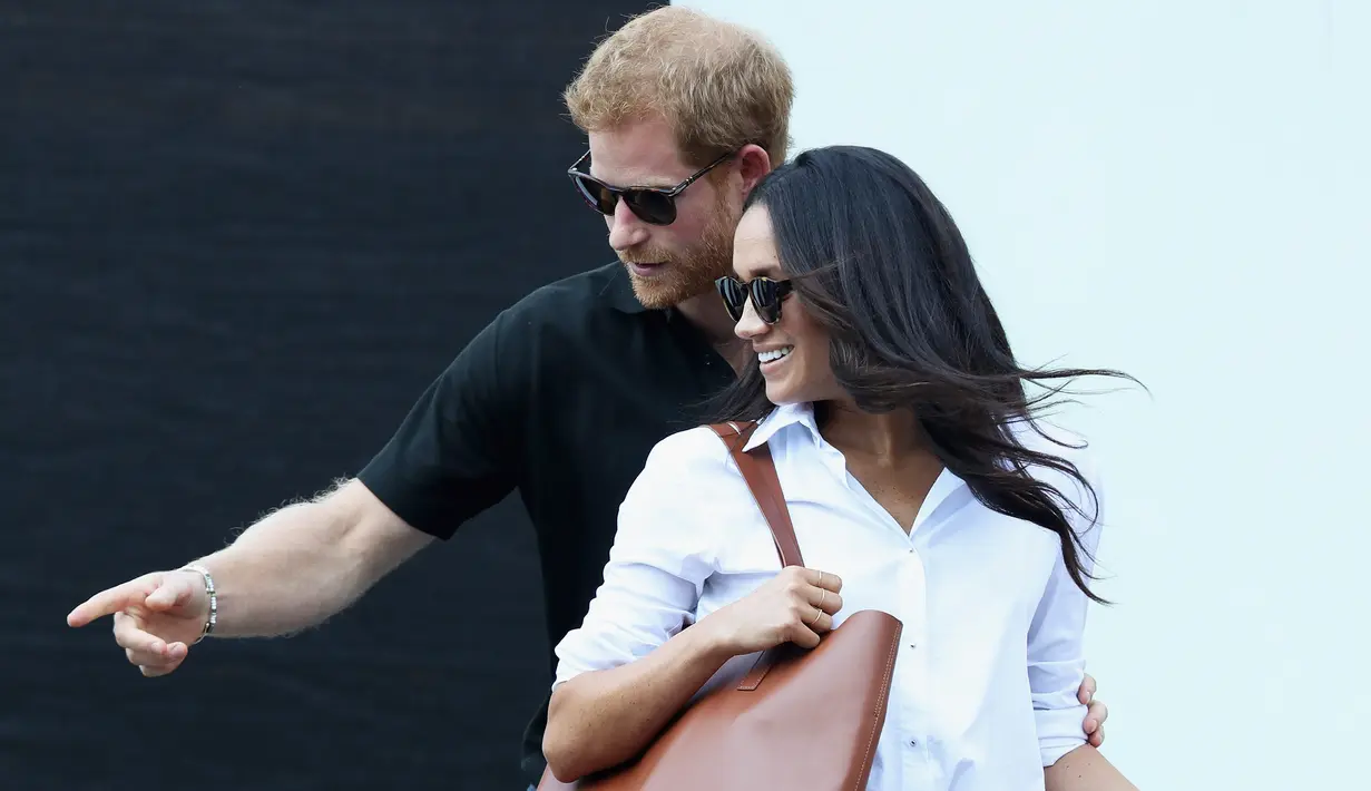 Pangeran Harry bersama Meghan Markle menghadiri pertandingan tenis kursi roda selama Invictus Games 2017 di Toronto, Kanada, Senin (25/9). Keduanya kompak mengenakan kacamata hitam selama menonton pertandingan. (Chris Jackson/GETTY IMAGES/AFP)