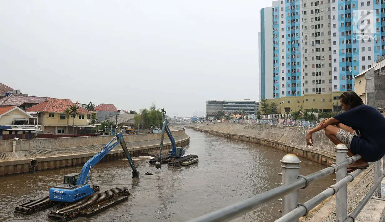 Warga melihat pengerukan endapan material lumpur dan sampah di Kali Ciliwung, Jakarta Timur, Kamis (18/10). Pengerukan lumpur dilakukan untuk antisipasi datangnya banjir saat musim hujan. (Merdeka.com/Imam Buhori)