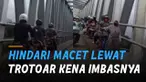 Berniat menghindari macet di jalan. beberapa pemotor justru tertahan oleh ibu-ibu berjalan sambil nuntun sepeda di trotoar.
