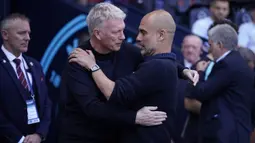 Pelatih Manchester City, Pep Guardiola (kanan) dan pelatih West Ham United, David Moyes berpelukan jelang dimulainya laga pekan terakhir Liga Inggris 2023/2024 di Etihad Stadium, Manchester, Minggu (19/5/2024). (AP Photo/Dave Thompson)