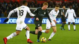 Gelandang Manchester City, Kevin De Bruyne, berusaha melewati pemain Swansea City, Jordan Ayew dan Tom Carroll pada laga Premier League di Stadion Liberty, Rabu (13/12/2017). Manchester City menang 4-0 atas Swansea City. (AFP/Geoff Caddick)