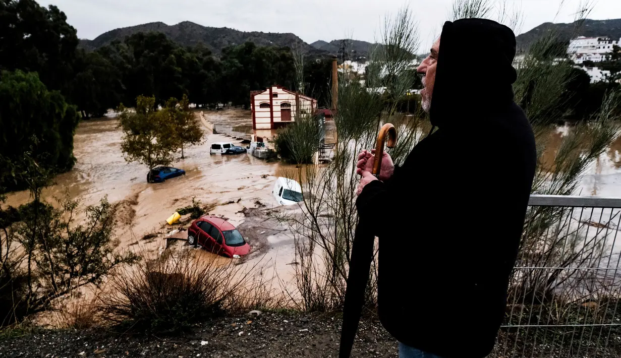 Seorang pria mengamati beberapa mobil yang tersapu air di kota Alora, Malaga, Spanyol, Selasa, 29 Oktober 2024. (AP Photo/Gregorio Marrero)