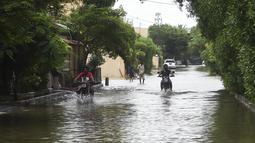 Pengendara sepeda motor melintasi jalan yang banjir setelah hujan muson lebat di Karachi (26/7/2022). Keadaan darurat cuaca diumumkan di Karachi karena hujan muson yang lebih deras dari biasanya terus melanda kota terbesar di Pakistan, membanjiri rumah-rumah dan membuat jalan-jalan tidak dapat dilalui. (AFP/Asif Hassan)