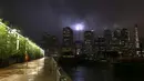 Seorang pria berlari di Brooklyn Bridge Park saat penghormatan 9/11 dalam Cahaya bersinar di langit Manhattan di New York City (10/9/2020). Tribute in Light tahunan National September 11 Memorial & Museum awalnya dibatalkan tahun ini karena pandemi COVID-19. (Michael M. Santiago/Getty Images/AFP)