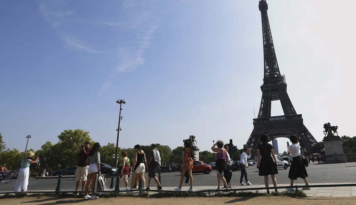 Wisatawan menuju ke Menara Eiffel di Paris, Rabu (31/8/2022). Pariwisata kembali dengan sepenuh hati ke Prancis musim panas ini, mengirimkan pendapatan melebihi tingkat pra-pandemi menurut data pemerintah yang dirilis minggu ini. (AP Photo/Aurelien Morissard)