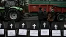 Para petani berdiri di dekat replika peti mati saat berunjuk rasa dan menutup jalan lingkar Bordeaux, Barat Daya Prancis, pada 24 Januari 2024. (Philippe LOPEZ/AFP)