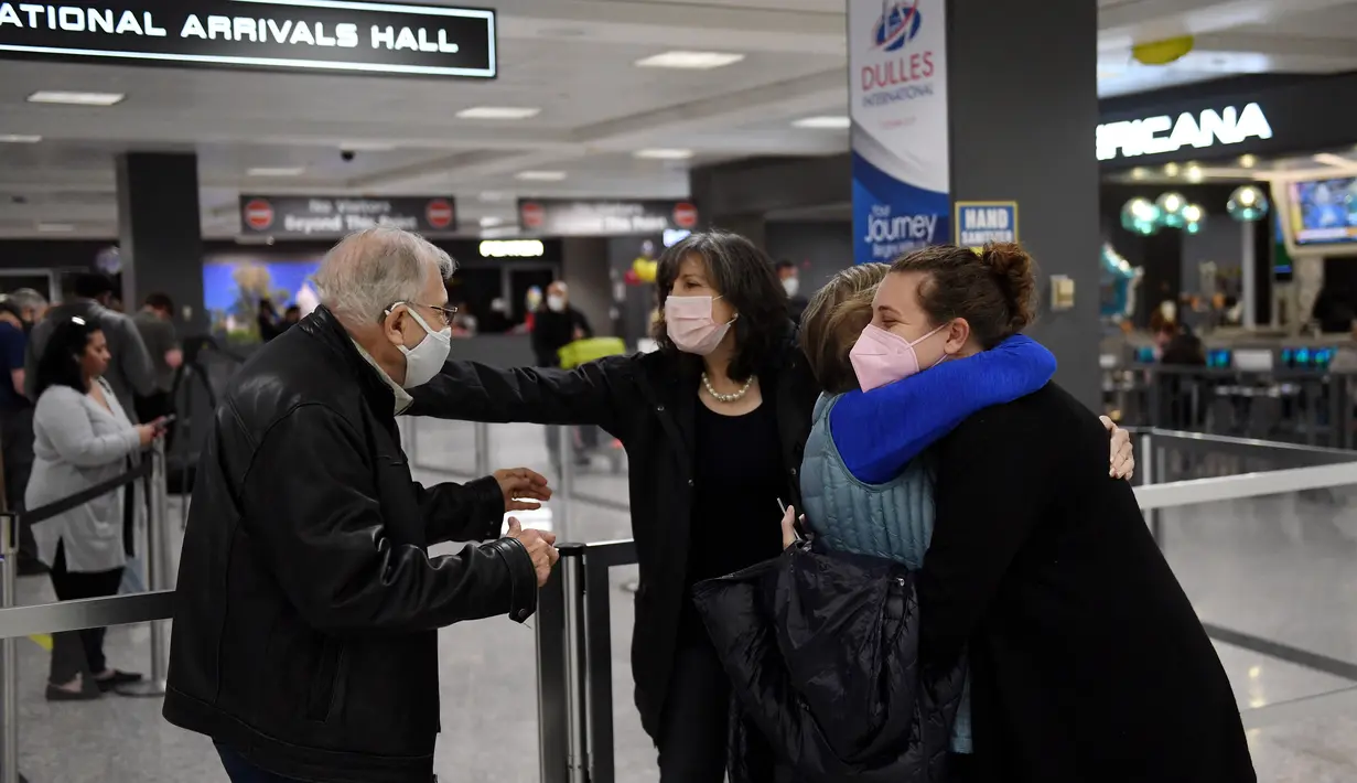 Anggota keluarga saling berpelukan ketika mereka bertemu kembali setelah terbang dari Amsterdam di Dulles International Bandara, Virginia, Senin (8/11/2021). AS membuka kembali perbatasannya mulai Senin untuk pengunjung asing, mengakhiri larangan masuk selama 20 bulan. (Olivier DOULIERY/AFP)
