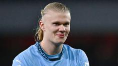 Pemain Manchester City memamerkan badge trofi Premier League kehadapan fans Arsenal. Hal itu dilakukan bomber asal Norwegia untuk membalas ejekan fans The Gunners. (AFP/Glyn Kirk)