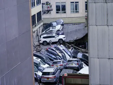 Petugas pemadam kebakaran terlihat bekerja di lokasi runtuhnya sebagian garasi parkir di Distrik Keuangan New York, Amerika Serikat, Selasa (18/4/2023). (AP Photo/Mary Altaffer)