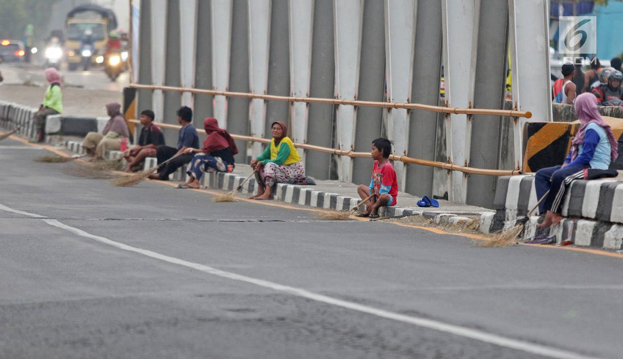 Warga membawa sapu menunggu pengguna jalan memberi sedekah dengan melempar uang di Jembatan Sewo, Jalur Pantura Sukra Indramayu, Jawa Barat, Senin (3/6/2019). Keberadaan pencari sedekah bisa membahayakan keselamatan pemudik serta pengguna jalan lainnya. (Liputan6.com/Herman Zakharia)