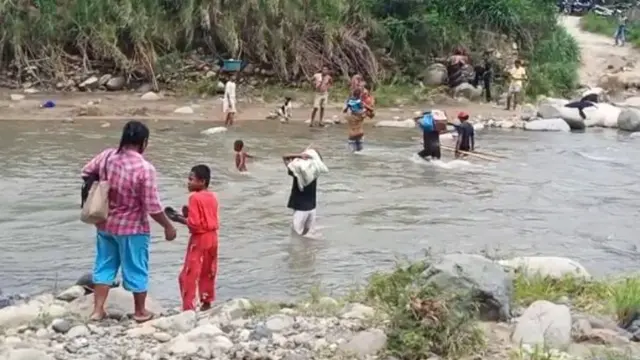 Warga desa Korobhera saat menyebrang di sungai gunakan jasa pikul barang. (Liputan6.com/Dionisius Wilibardus)