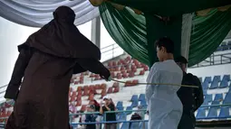 Seorang pria dicambuk setelah ketahuan melakukan hubungan seks pranikah di sebuah stadion di Lhokseumawe di provinsi Aceh (31/7/2019). Dua pria dan seorang wanita dicambuk secara terbuka sebanyak 100 kali karena melanggar hukum Islam di daerah tersebut. (AFP Photo/Rahmad Mirza)
