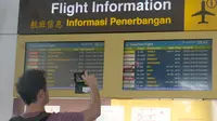 Calon penumpang mengambil gambar papan informasi penundaan penerbangan di Bandara Ngurah Rai, Bali, Jumat (29/6). Pihak pengelola menutup sementara aktivitas bandara maupun penerbangan karena gangguan abu vulkanis erupsi Gunung Agung. (AFP/GEDE ARDIASA)