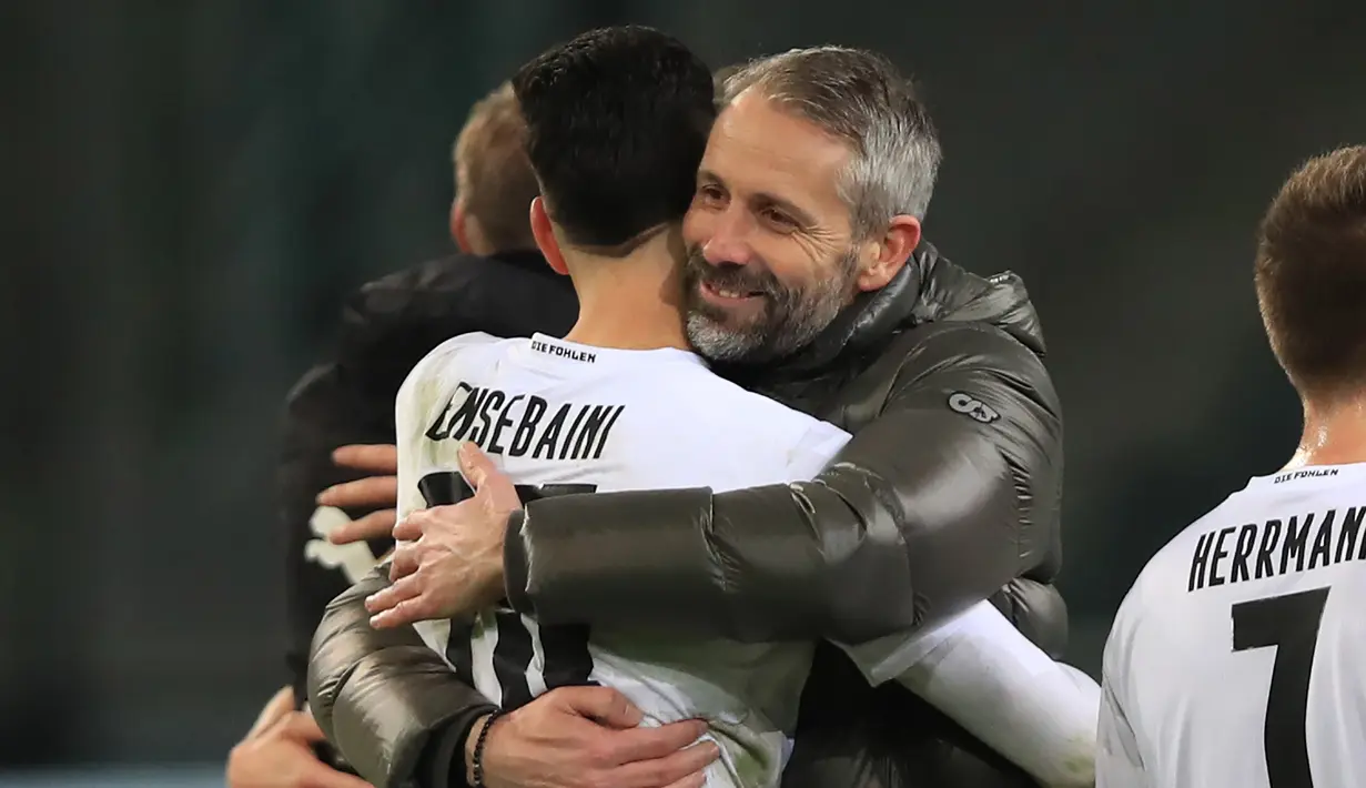 Manajer tim Borussia Moenchengladbach, Marco Rose memeluk bek Ramy Bensebaini usai berakhirnya laga lanjutan Liga Jerman 2020/21 pekan ke-18 melawan Borussia Dortmund di Borussia Park, Jumat (22/1/2021). Moenchengladbach menang 4-2 atas Dortmund. (AFP/Wolfgang Rattay/Pool)