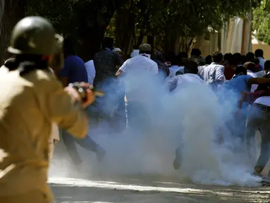 Para pengunjuk rasa melarikan diri ketika polisi menembakkan gas air mata ke arah mereka saat protes terhadap pembunuhan yang terjadi baru-baru ini di Kashmir, Jumat (5/8). (REUTERS / Danish Ismail)