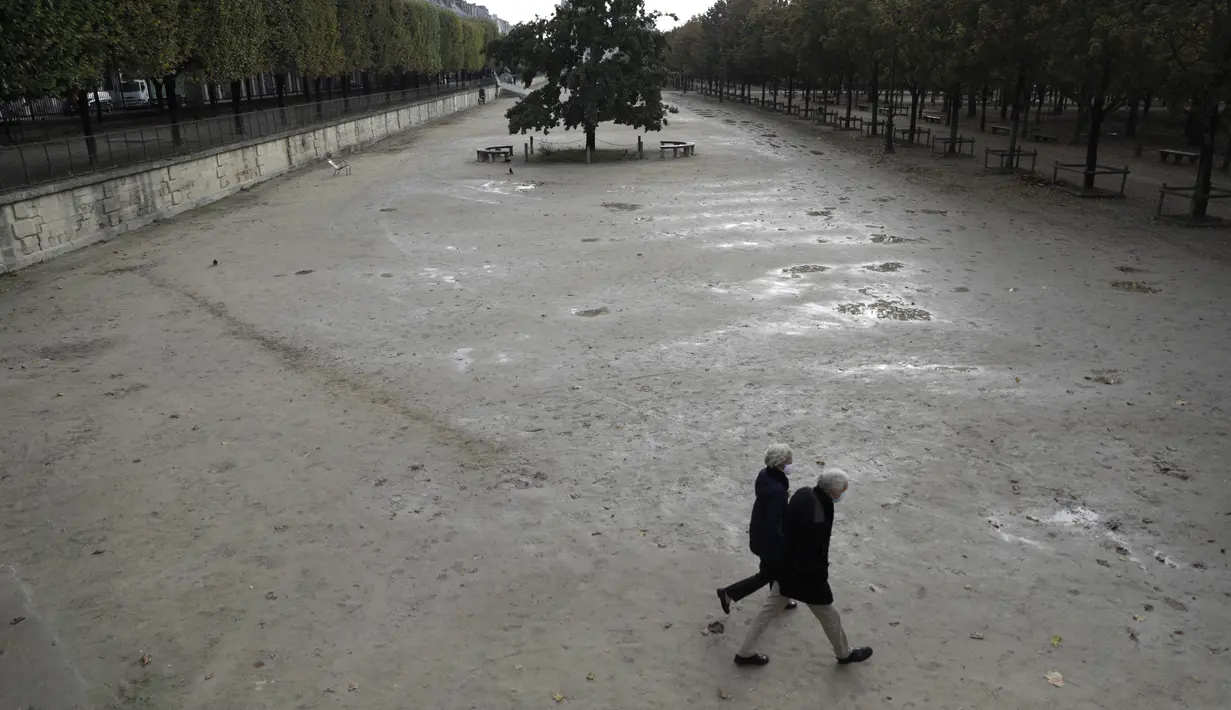 Orang-orang berjalan di taman Tuileries yang kosong di Paris (14/10/2020). Presiden Prancis Emmanuel Macron memberikan wawancara televisi nasional Rabu malam untuk berbicara tentang virus, yang pertama dalam beberapa bulan. (AP Photo/Lewis Joly)