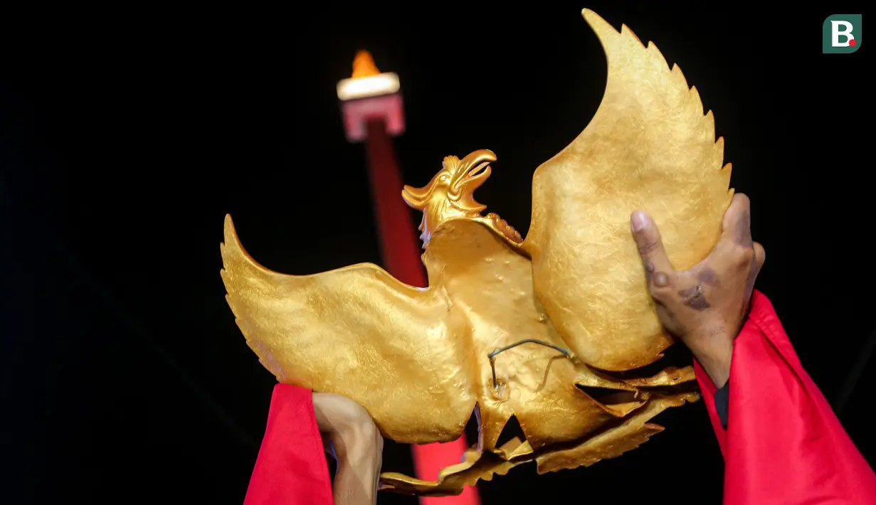 Seorang suporter Timnas Indonesia U-23 mengangkat patung Garuda Pancasila saat nonton bareng pertandingan perebutan juara ketiga Piala Asia U-23 2024 antara Timnas Indonesia U-23 melawan Irak U-23 di Kompleks Monumen Nasional (Monas), Jakarta, Kamis (03/05/2024). (Bola.com/Bagaskara Lazuardi)