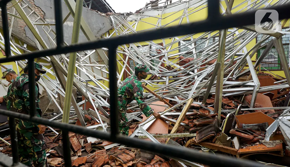 Petugas Babinsa TNI AD membersihkan reruntuhan atap yang ambruk akibat gempa di salah satu ruang kelas di MAN 2 Malang, Turen, Kabupaten Malang, Minggu (11/4/2021). Gempa bermagnitudo 6,1 yang terjadi pada Sabtu (10/9) siang menyebabkan kerusakan berat di MAN 2 Malang. (merdeka.com/Nanda F. Ibrahim)