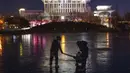 Warga menarik seorang anak melintasi danau beku dekat Olympics Green di Beijing, China, 3 Januari 2022. Libur Tahun Baru dimanfaatkan warga untuk bermain ice skating di sungai dan danau yang membeku. (AP Photo/Ng Han Guan)