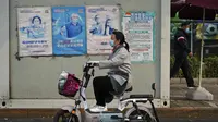 Seorang wanita melewati fasilitas pengujian virus corona yang memajang poster yang mempromosikan vaksinasi COVID-19 di Beijing, Rabu (26/10/2022). Kota Shanghai di China mulai memberikan vaksin COVID-19 yang dapat dihirup pada hari Rabu di tempat yang tampaknya menjadi yang pertama di dunia. (AP Photo/Andy Wong)