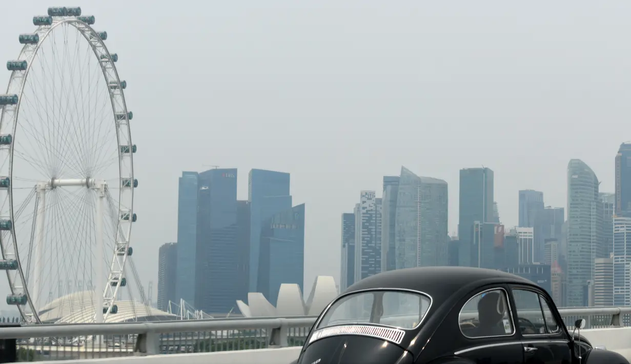 Sebuah kendaraan melintas saat kabut asap menyelimuti kota Singapura (15/9/2019). Polusi dari kebakaran hutan di Indonesia mendorong kualitas udara Singapura ke tingkat yang tidak sehat untuk pertama kalinya dalam tiga tahun. (AFP Photo/Roslan Rahman)
