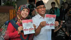 Mohammad Idris dan istri memegang surat suara sebelum melakukan pencoblosan di TPS 077 di Perum Pondok Duta, Depok, (9/12). Idris akan bersaing dengan pasangan nomor urut satu yaitu Dimas Oky Nugroho dan Babai Suhaimi. (Liputan6.com/Yoppy Renato)
