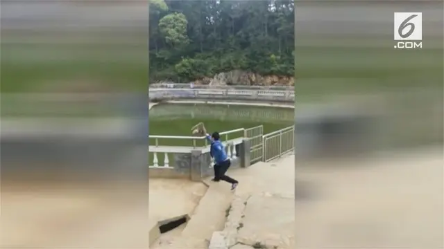 Seorang pria membuat ulah di Kuil Xitian, Dehua, China, dengan mendorong seekor monyet ke kolam.