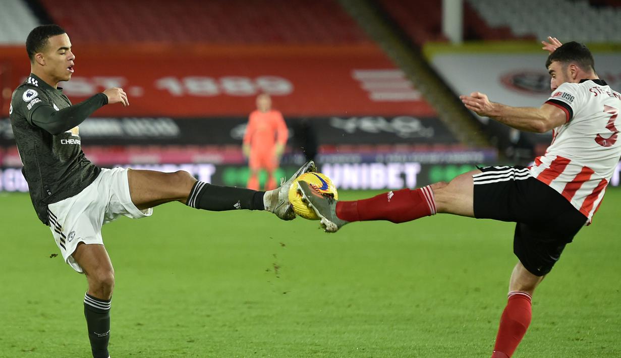 Striker Manchester United, Mason Greenwood (kiri), berebut bola dengan bek Sheffield United, Enda Stevens, dalam laga lanjutan Liga Inggris 2020/21 pekan ke-13 di Bramall Lane, Sheffield, Kamis (17/12/2020). Manchester United menang 3-2 atas Sheffield United. (AFP/Peter Powell/Pool)