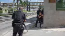 Para polisi militer Rio de Janeiro berlindung di sebuah tembok saat melakukan operasi penggerebekan di daerah kumuh Cidade de Deus di Rio de Janeiro, Brasil (1/2). (AFP Photo/Mauro Pimentel)