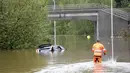 Personel penyelamat mendekati mobil yang terendam air banjir di jalan utama di Falun, Swedia, Rabu (18/8/2021). Hujan deras di Swedia timur telah menggenangi beberapa area pemukiman, dengan beberapa jalan dan jembatan tergenang saat hujan terus turun. (Ulf Palm / TT via AP)