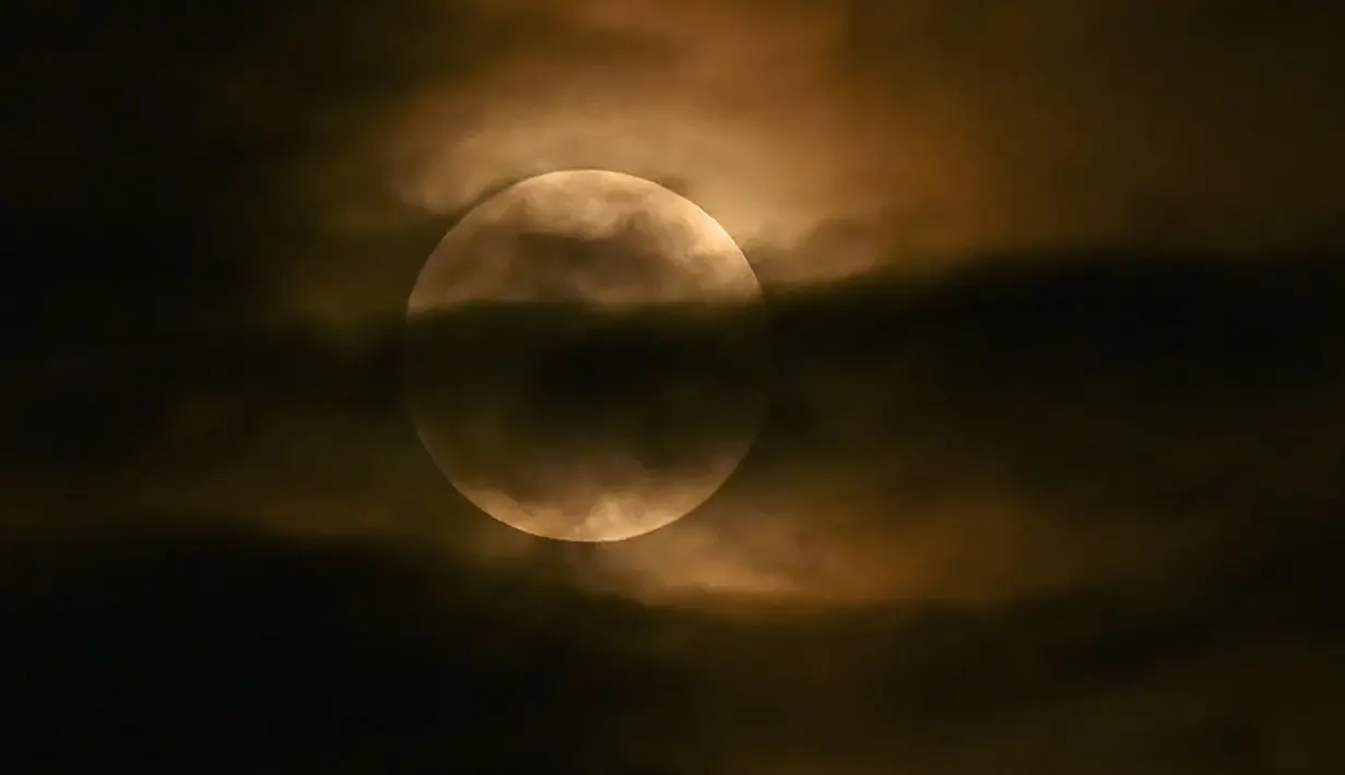 Bulan terlihat melalui awan saat gerhana bulan sebagian di Srinagar, India, Jumat (5/5/2023). Gerhana Bulan Penumbra akan muncul pada Jumat (5/5/) hingga Sabtu (6/5) dinihari. (TAUSEEF MUSTAFA / AFP)