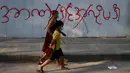 Pejalan kaki melewati grafiti bertuliskan "tidak ingin kediktatoran" di Yangon, Myanmar (4/2/2021).   Pemerintah Militer Myanmar menuduh Facebook berkontribusi terhadap ketidastabilan di negeri tersebut. (AP Photo)