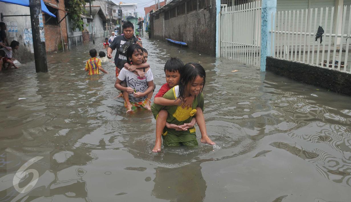 Sejumlah anak menggendong adiknya melewati banjir di Rawa Buaya, Jakarta, Minggu (28/2/2016). Banjir akibat luapan Kali Mookervart ini menyebabkan ratusan rumah warga tergenang air rata-rata satu meter. (Liputan6.com/Gempur M Surya)