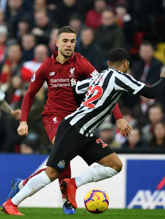 Gelandang Liverpool, Jordan Henderson berebut bola dengan bek Newcastle United, DeAndre Yedlin pada pertandingan Liga Inggris di Stadion Anfield, Rabu (26/12). Liverpool bertahan di puncak klasemen setelah menghajar Newcastle United 4-0. (Paul ELLIS/AFP)