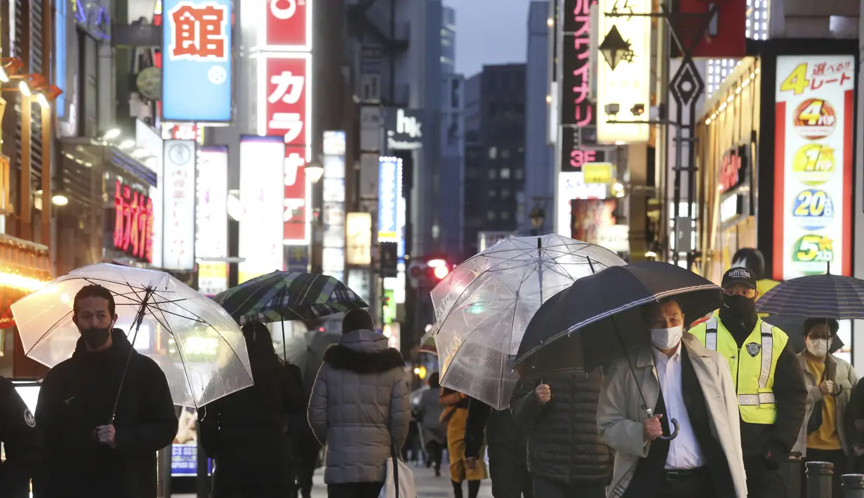 Orang-orang yang mengenakan masker untuk membantu melindungi diri dari penyebaran virus corona berjalan di sepanjang jalan yang dipenuhi bar dan restoran di Tokyo, Selasa (22/3/2022). Langkah-langkah pra-darurat untuk mencegah wabah Covid-19 telah dicabut. (AP Photo/Koji Sasahara)