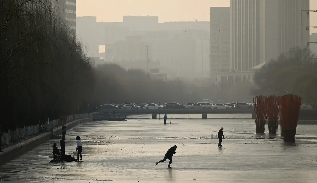 Sejumlah warga bermain ice skating di sungai yang membeku di Beijing, China (10/1). Akibat membeku, Sungai ini menjadi objek wisata dadakan. (AFP Photo/Wang Zhao)