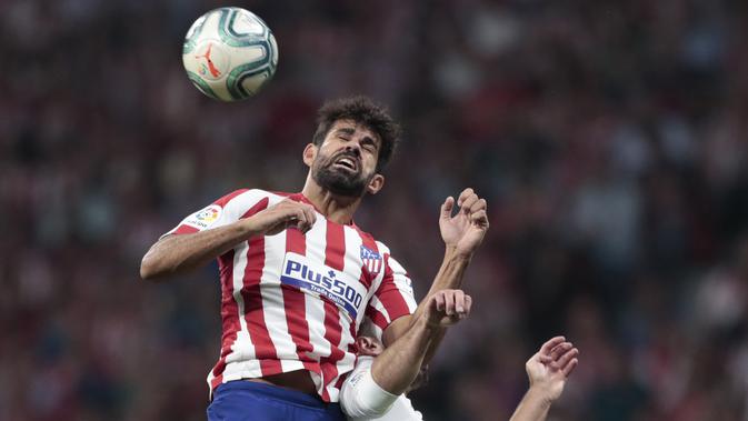 Penyerang Atletico Madrid, Diego Costa berebut bola udara dengan bek Real Madrid, Dani Carvajal pada pertandingan lanjutan La Liga di stadion Wanda Metropolitano, Spanyol (28/9/2019). Madrid dan Atletico bermain imbang 0-0. (AP Photo/Bernat Armangue)