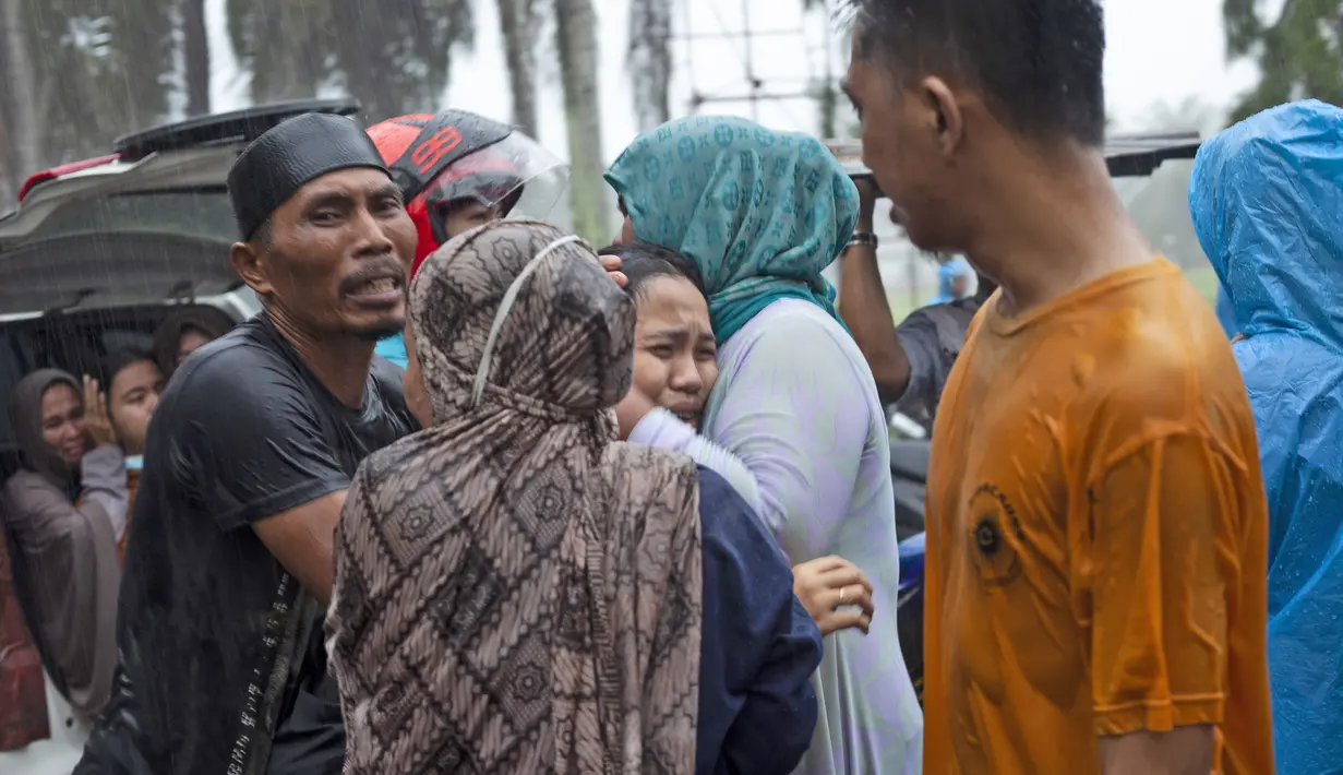 Keluarga korban menangis histeris saat jenazah diambil dari reruntuhan bangunan di daerah yang terkena gempa bumi di Mamuju, Sulawesi Barat, Jumat (15/1/2021). Setidaknya 34 orang meninggal dunia akibat gempa dahsyat tersebut. (AP Photo/Yusuf Wahil)