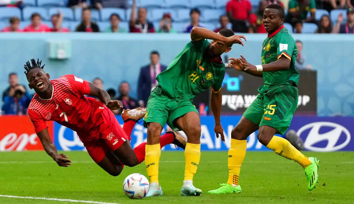 Pemain Swiss Breel Embolo (kiri) berebut bola dengan pemain Kamerun Jean-Charles Castelletto (tengah) dan Tolo Nouhou pada pertandingan sepak bola Grup G Piala Dunia 2022 di Stadion Al Janoub, Al Wakrah, Qatar, Kamis (24/11/2022). Swiss mengalahkan Kamerun dengan skor 1-0. (AP Photo/Matthias Schrader)