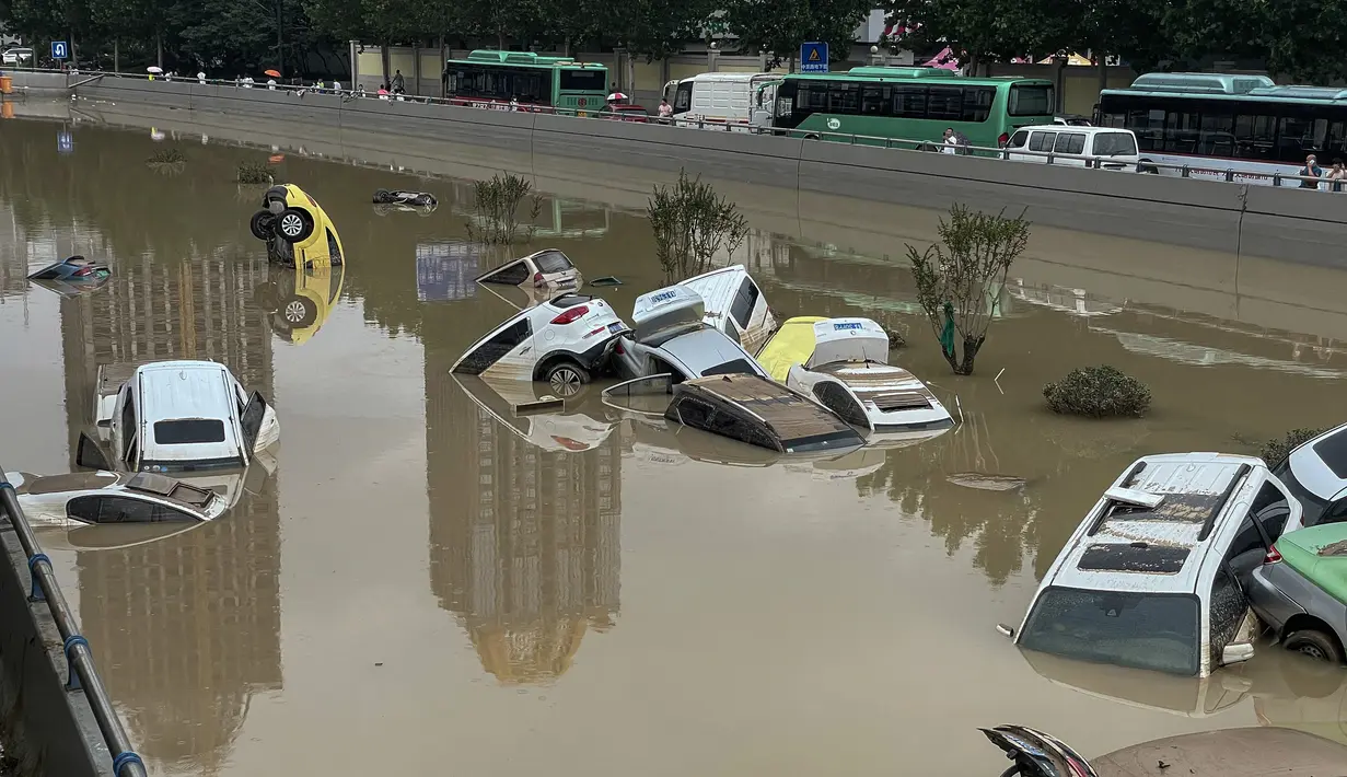 Mobil-mobil terendam banjir setelah hujan lebat melanda kota Zhengzhou di provinsi Henan tengah China (21/7/2021). Luapan sungai menggenangi jalan-jalan dan membuat kendaraan terbawa arus setelah curah hujan 200 mm turun dalam satu jam. (AFP/STR)