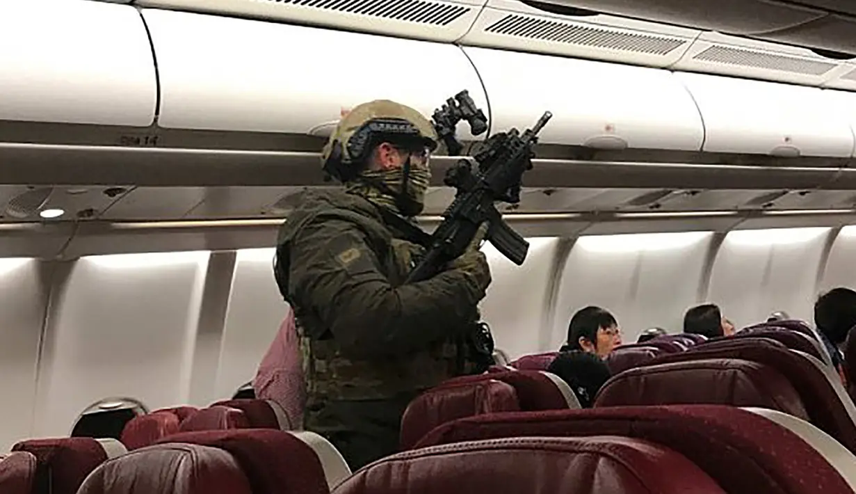 Polisi bersenjata lengkap berjalan di dalam pesawat Malaysia Airlines Flight MH128 untuk menangkap seorang pria Sri Lanka setelah penerbangan tersebut melakukan pendaratan darurat di Melbourne, Australia (1/6). (Andrew Leconcelli/AFP)