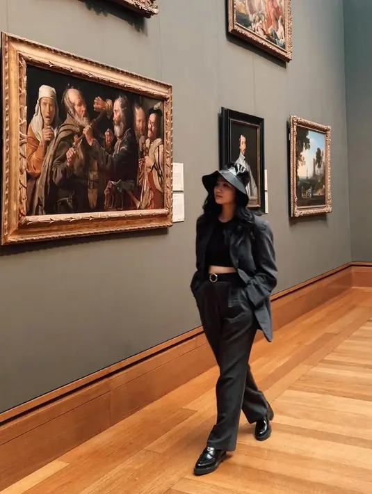 Winter look, but make it fashionable. Febby Rastanty tampak mengunjungi museum dengan all black outfit. Tank top ditumpuk dengan blazer, dipadu dengan celana panjang, alas kaki, dan topi lebar yang semuanya berwarna hitam. Foto: Instagram.