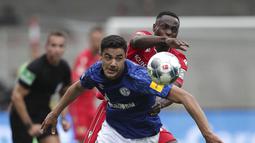 Pemain Union Berlin, Anthony Ujah, berebut bola dengan pemain Schalke, Ozan Kabak, pada laga Bundesliga di Weserstadion Minggu (7/6/2020). Kedua tim bermain imbang 1-1. (AP/Michael Sohn)