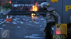 Seorang petugas mengamati aksi mahasiswa memperingati Hari Sumpah Pemuda di depan Gedung DPR, Senayan, Jakarta, Rabu (28/10/2015). Dalam aksinya para mahasiswa membakar ban. (Liputan6.com/Johan Tallo) 