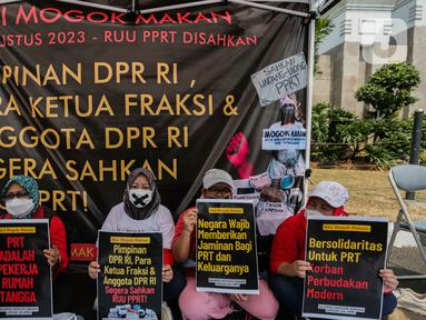 Sejumlah anggota aliansi Mogok Makan Untuk Undang Undang Perlindungan Pekerja Rumah Tangga (UU PPRT) membentangkan poster saat aksi di depan Gedung DPR, Jakarta, Senin (14/8/2023). (Liputan6.com/Faizal Fanani)