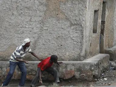 Pengunjuk rasa sembunyi dibalik dinding dengan membawa batu bersiap menyerang petugas di Bujumbura, Burundi, (20/5/2015). Kerusuhan dipicu protes terhadap Presiden Burundi Pierre Nkurunziza untuk upayanya menambah masa jabatan. (REUTERS/Goran Tomasevic)
