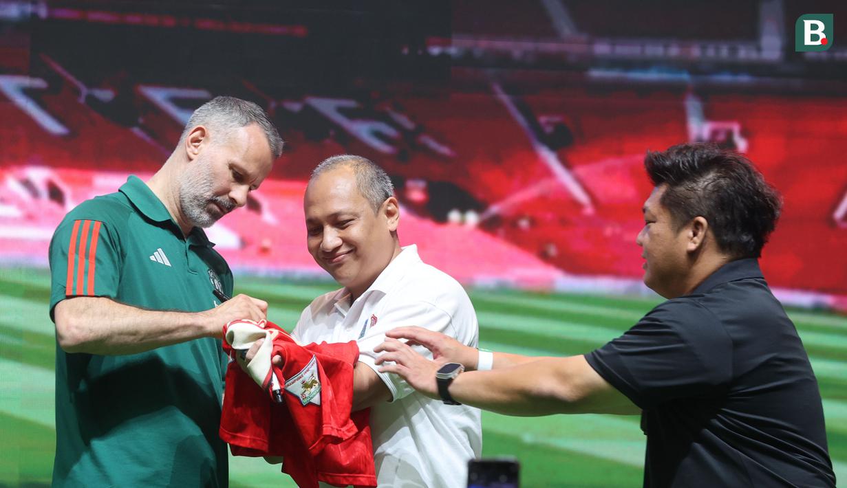 Legenda Manchester United (MU), Ryan Giggs, membubuhkan tanda tangan di jersey fans dalam acara peluncuran kartu kredit Maybank yang berkolaborasi dengan MU di Jakarta Convention Center (JCC), Senayan, Jakarta, Sabtu (18/5/2024). (Bola.com/M Iqbal Ichsan)